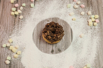 Dona dulce de chocolate y brownie cubierta de chispas y malvaviscos con azucar