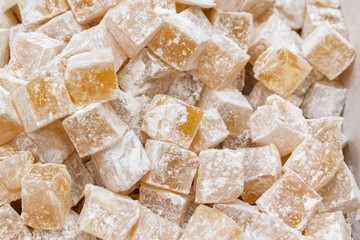 Heap of sweet cubes in powdered sugar. Turkish delight or lokum is a confections based on a gel of starch and sugar. Selective focus.