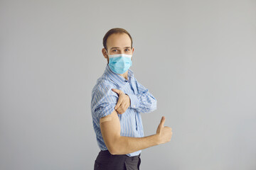 Studio portrait happy man in face mask doing thumbs up gesture satisfied with coronavirus vaccine....