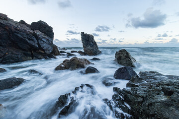Fototapeta na wymiar Wave water coming in between rock formation in the shore.