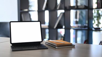 Mock up computer tablet and notebooks on wooden table in modern office.