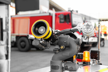 Modern high-tech firefighting robot with a hose for penetration into especially dangerous areas and extinguishing fires near red fire truck. Technology, transport and robotics concept