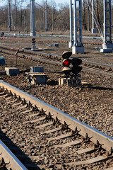 Semaphore shining red light between railway tracks and gravel embankment closeup vertical...