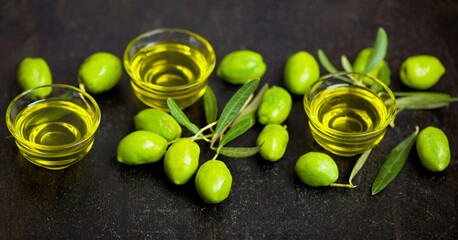 Olive oil and olive branch on black background
