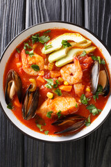 Sopa de Mariscos Seafood Soup closeup in the plate on the table. Vertical top view from above