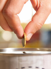 A female hand about to introduce a coin in a money box. Save money concept banner.
