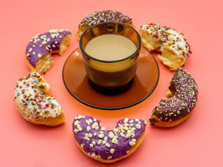 cup of coffee with half donuts around on pink background