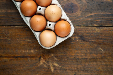 Chicken eggs in a tray on a wooden table.