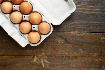 Chicken eggs in a tray on a wooden table.