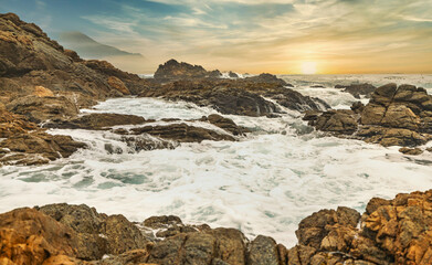 Fototapeta na wymiar Beautiful seascape, ocean views, rocky coast, sunlight on the horizon. Composition of nature. Sunset scenery background. Cloudy sky. Water Reflection. California Seashore.