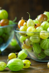 Ripe gooseberry in a glass plate, place for text, top view, summer harvest of berries.