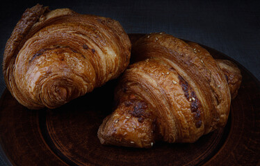 Fresh crispy croissants on a clay dish.