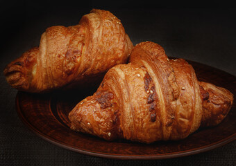 Two beautiful croissants on a clay dish.