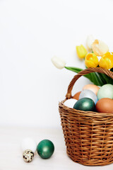 Easter eggs and yellow tulips in a vase on a light background cropped view