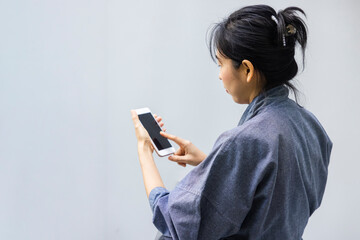 A woman shopping online on her sofa at home with a smartphone using and tap the screen to verify the identity. Concept about business. over shoulder shot