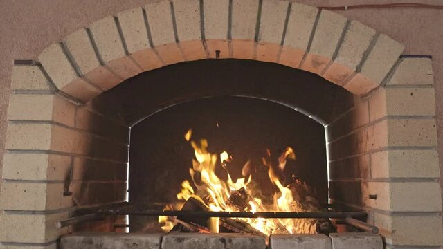 Light large brick brazier with bright blazing fire and burning black and coal logs, 4X slow-motion
