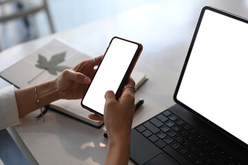 Close up view of businesswoman hands holding mock up smart phone with white screen.
