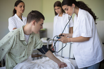 Young student in hospital measures the patient's pressure. - 426804327