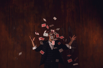 Fototapeta na wymiar Close-up portrait of young man with gambling cards. Handsome guy throws up with card. Clever hands of magician on brown texture background. Concept of entertainment and Hobbies. Copy space for site