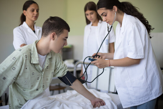 Young student in hospital measures the patient's pressure.
