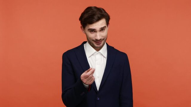Young businessman showing money gesture, planning big income and looking cunning smile, pretending scattering banknotes with arrogant expression. Indoor studio shot isolated on orange background