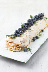 Meringue dessert Pavlova cake with fresh berries on top on a light wooden background.