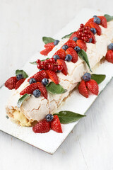 Meringue roll Pavlova cake with cream and raspberries, blackberries and blueberries