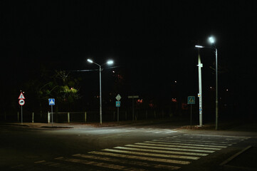 Pedestrian crossing at night in the illumination of street lamps in a post-Soviet city, devastation - Powered by Adobe