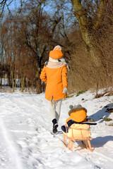 Matka z z dzieckiem na sankach w parku. © Miosz