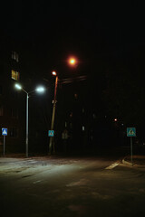 Pedestrian crossing at night in the illumination of street lamps in a post-Soviet city, devastation