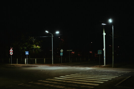 Pedestrian crossing at night in the illumination of street lamps in a post-Soviet city, devastation