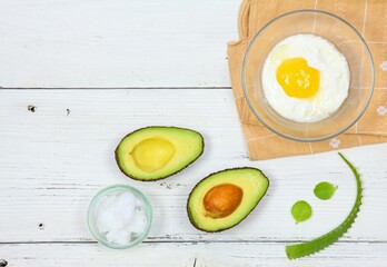 Natural ingredients for smoothing, softening and hydrating your hair.  Avocado, aloe vera,  yogurt, coconut oil and  egg yolk for hair mask, flat lay, copy space.