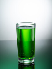 tall transparent glass with green tarragon lemonade on a light background