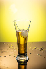 tall transparent glass with beer and a splash from falling ice breaks, fragments