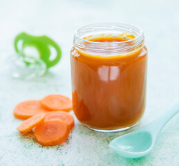 Fototapeta na wymiar Baby carrot mashed with spoon in glass jar