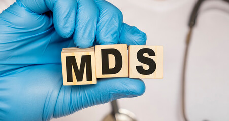 MDS Myelo dysplastic syndrome - word from wooden blocks with letters holding by a doctor's hands in medical protective gloves. Medical concept.