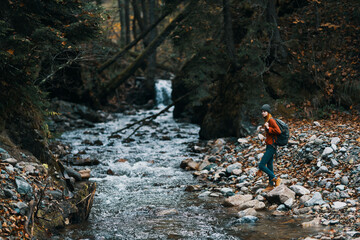 woman in a sweater hat near the river and trees in the background