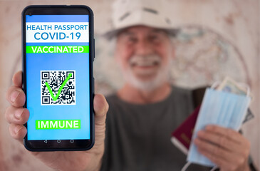 Smiling traveler man shows health passport app for people vaccinated against coronavirus, ready to go