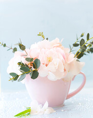 A pink cup filled with flowers: hydrangea, veronica, eucolyptus sprigs
