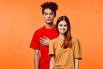 guy and girl in colorful t-shirts fun studio orange background