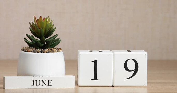 Wooden calendar with an important event for June 19, a woman's hand sets the date on the calendar. Summer season.	