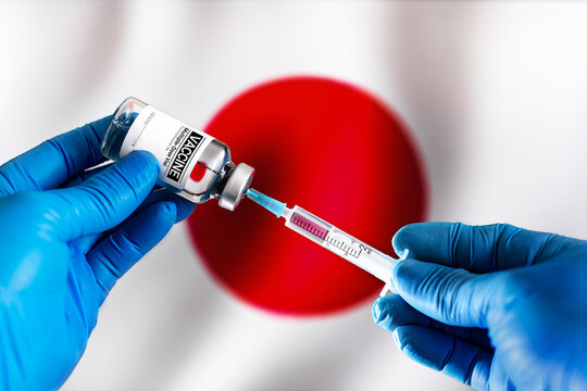 Injecting Dose Of Vaccine In Syringe For Covid-19 Over The Japanese Flag. Doctor With Vial Of The Vaccine For Covid-19 And Japan Flag In The Background. 