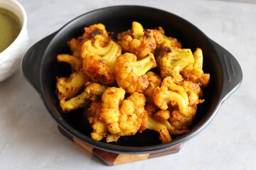Gobi or Gobhi Tandoori. Masala Roasted cauliflower is a popular Indian vegetarian starter dish served with mint and coriander chutney. copy space.