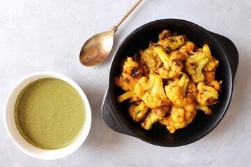Gobi or Gobhi Tandoori. Masala Roasted cauliflower is a popular Indian vegetarian starter dish served with mint and coriander chutney. copy space.