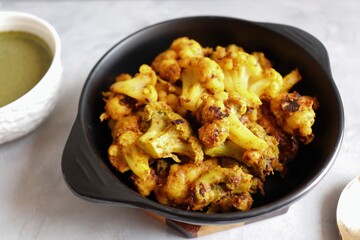 Gobi or Gobhi Tandoori. Masala Roasted cauliflower is a popular Indian vegetarian starter dish served with mint and coriander chutney. copy space.