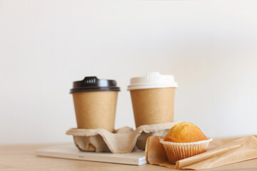 two paper cups with coffee and a cupcake. breakfast for two. to be in love. take care of your partner. move to the guy. coffee for girlfriend.Eco friendly paper coffee cup with black lid on
