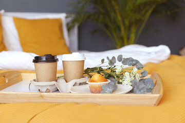 breakfast in bed for two. two paper takana with coffee cupcake. white and orange color