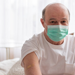 Senior hispanic man wearing face mask showing vaccinated arm.