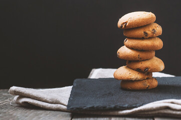 Chocolate chip stack cookies on a plate and tablecloth black background