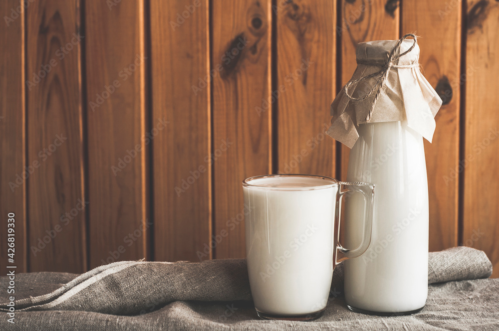 Wall mural fresh homemade milk on a brown wooden background. a eco bottle of milk and glass of milk on a tablec